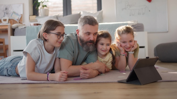Video of father with three daughters watching tv show on tablet. Girl dad concept.