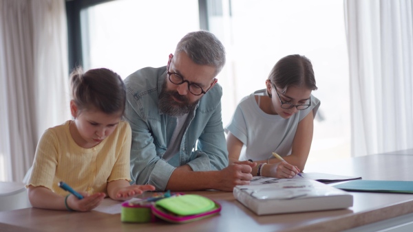 Father helping his daughters with their homework.