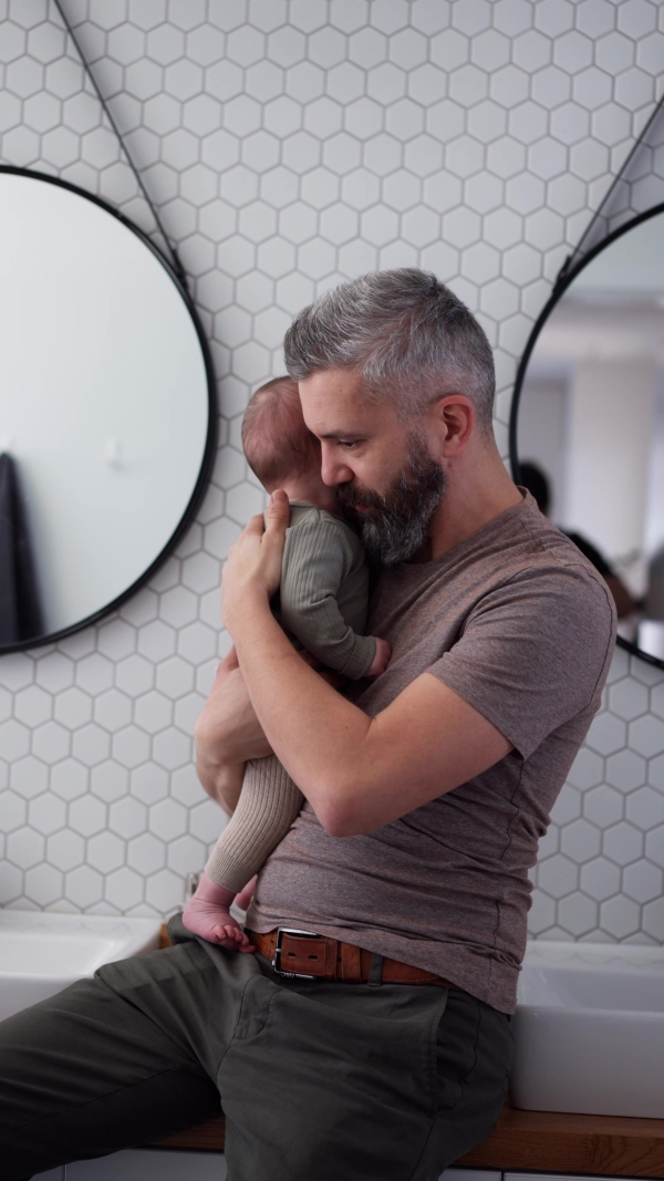 Father comforting his crying baby son, holding him in arms.