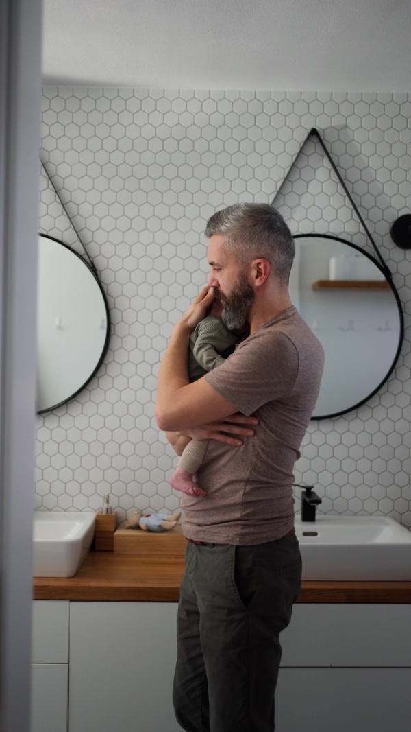 Father comforting his crying baby son, holding him in arms.