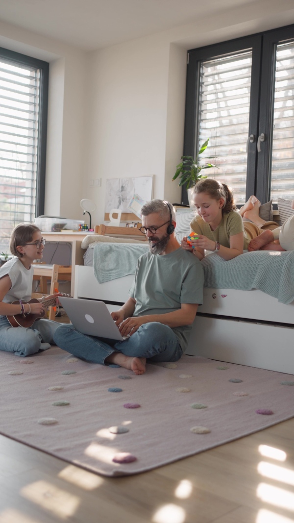 Father with three daughters trying to work from homeoffice. Girl dad concept.