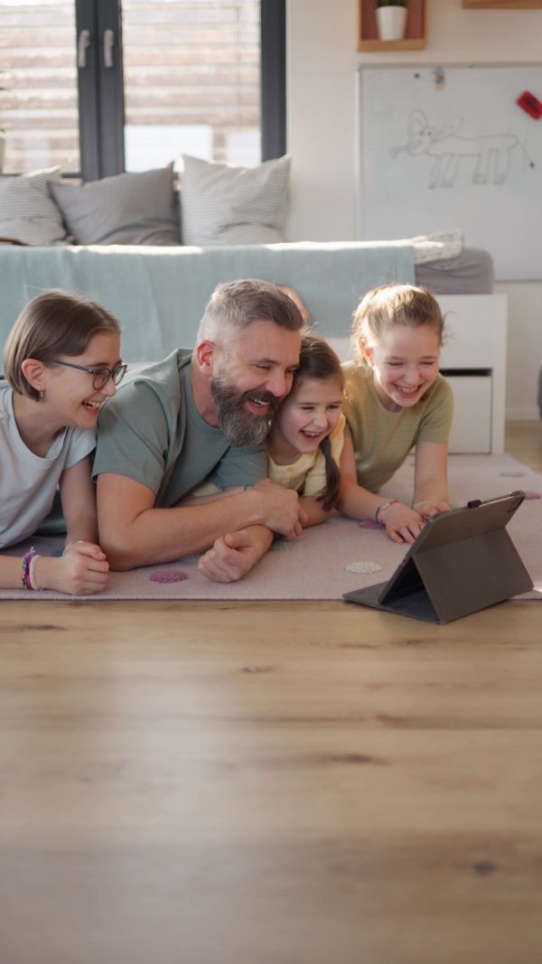 Video of father with three daughters watching tv show on tablet. Girl dad concept.