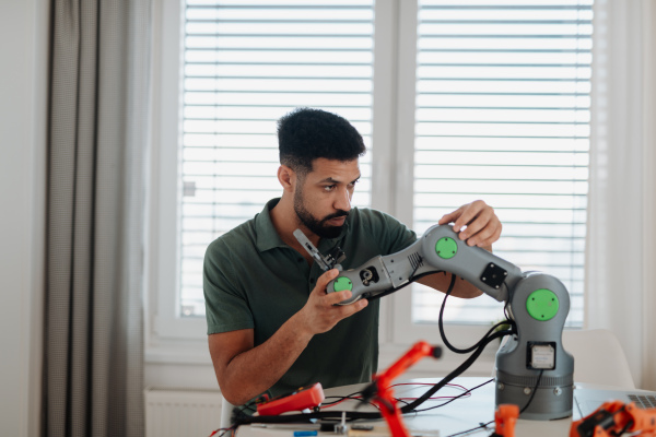 Young engineer building and programming a robotic arm at home. Robotics concept.