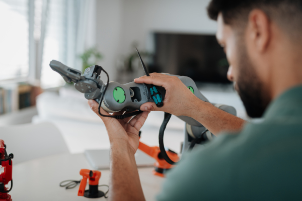 Close up of engineer's hands building and programming a robotic arm at home. Robotics concept.