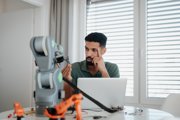 Engineer struggling with a technical problem while building robotic arm at home.
