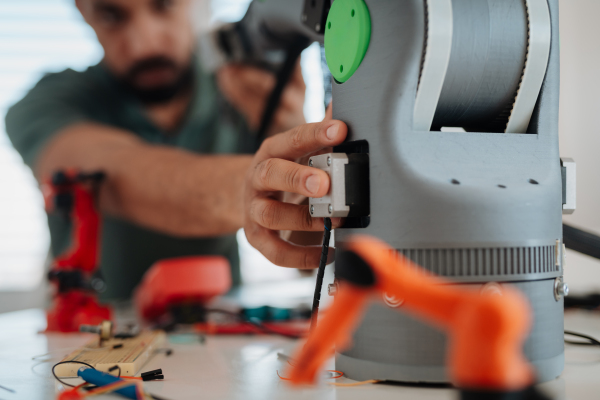 Close up of engineer's hands building and programming a robotic arm at home. Robotics concept.