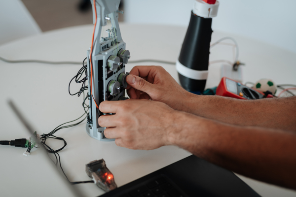 Close up of engineer's hands building and programming a robotic arm at home. Robotics concept.