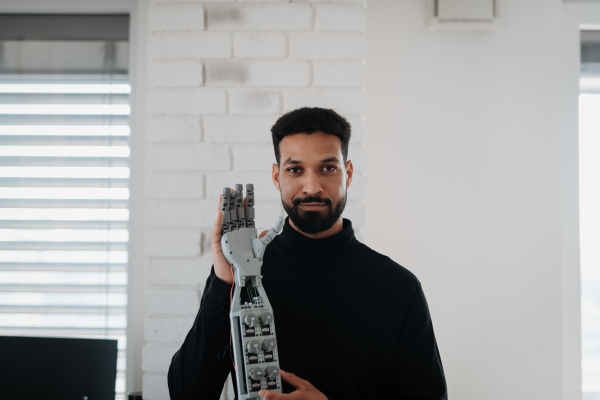 Portrait of young engineer holding robotic arm. Robotics concept.