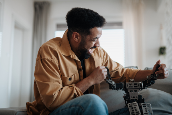 Handsome man holding small robot and dancing with it, laughing.