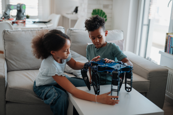 Kids building their first homemade robot at home. Educational robotic kit for children.
