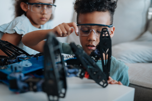 Kids building their first homemade robot at home. Educational robotic kit for children.