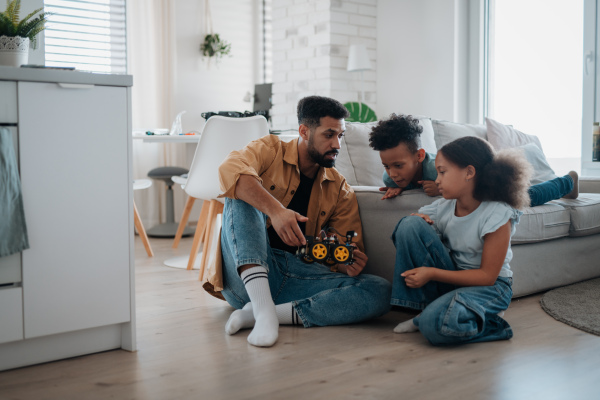 Father teaching kids about STEM, robotics, and discussing technology at home.