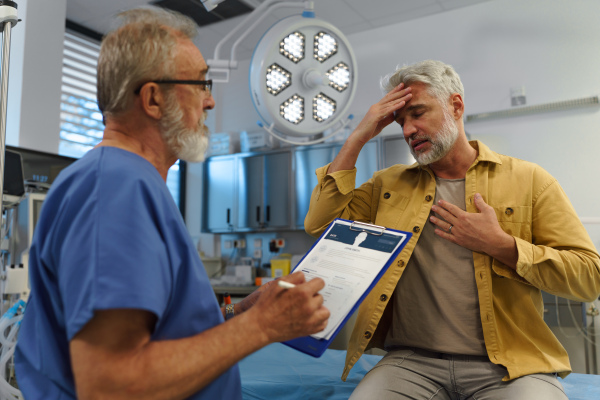 Patient sitting on examination table, describing health problems and symptoms to doctor.