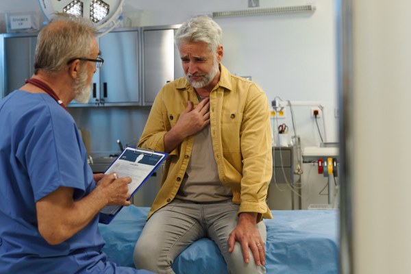 Patient sitting on examination table, describing health problems, chest pain to doctor.