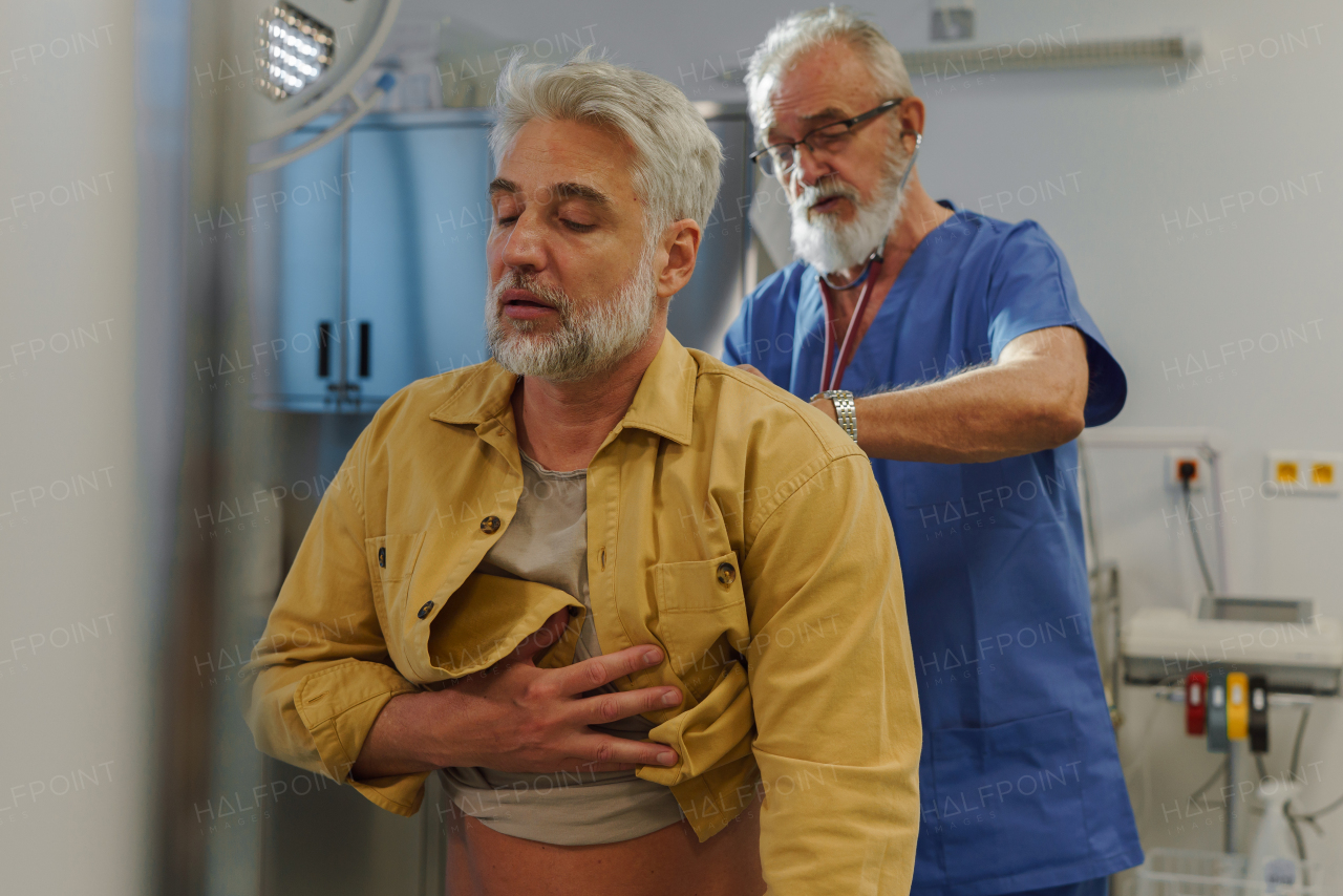Doctor examining sick patient, listening to breathing with stethoscope.