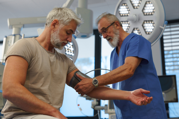 Doctor taking patient's blood pressure using a digital blood pressure monitor.