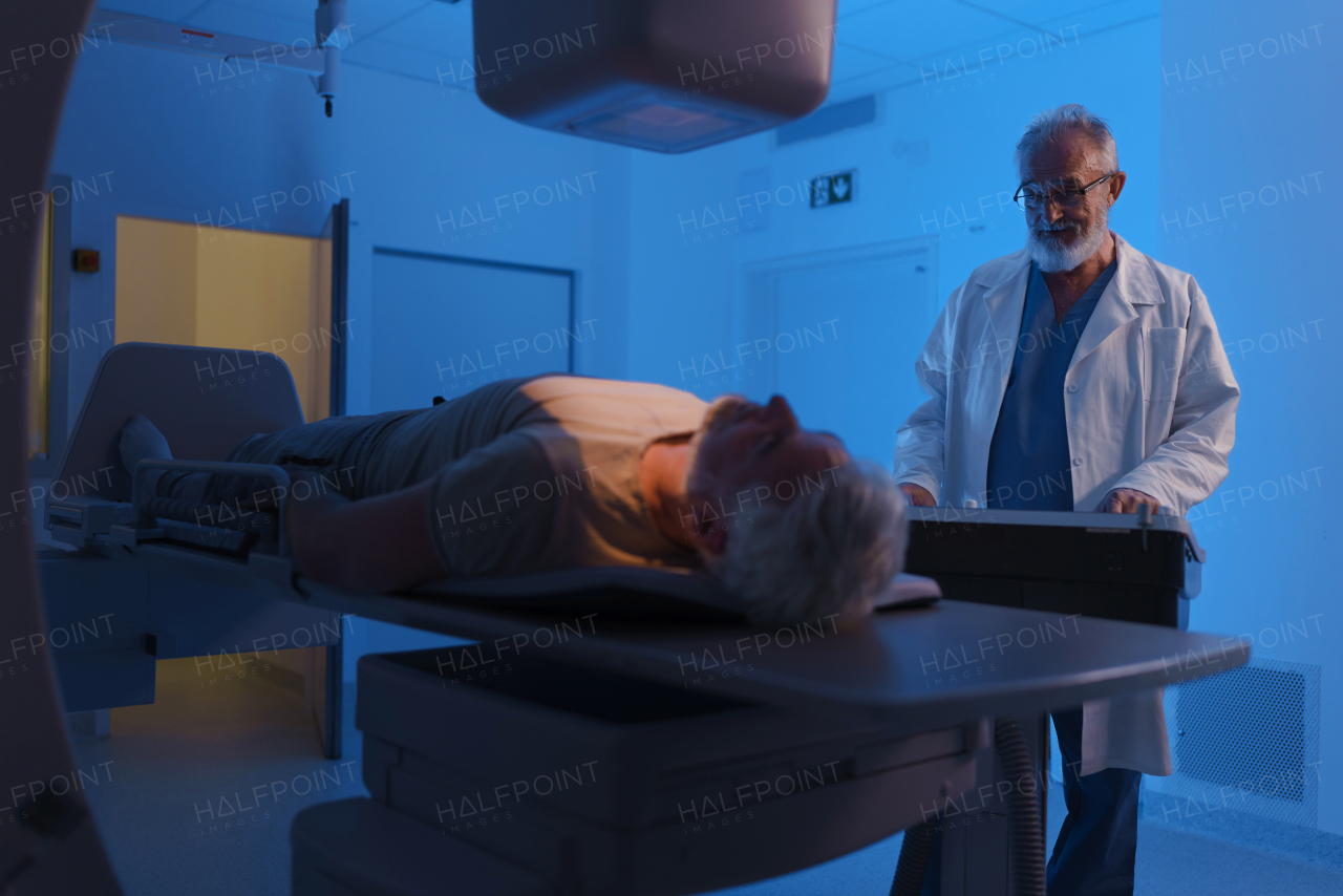 Male patient undergoing X-ray examination using a tilting radiographic wall stand.