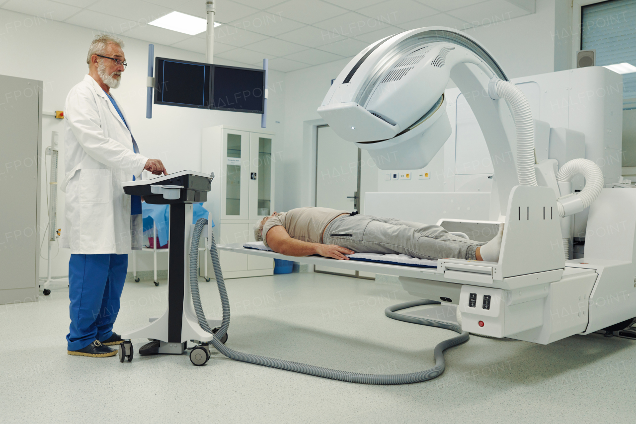Male patient undergoing X-ray examination using a tilting radiographic wall stand.