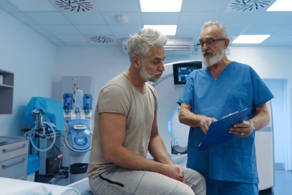 Doctor explaining CT scan results to male patient in hospital setting