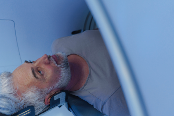 Male patient undergoing CT scan examination in a hospital.