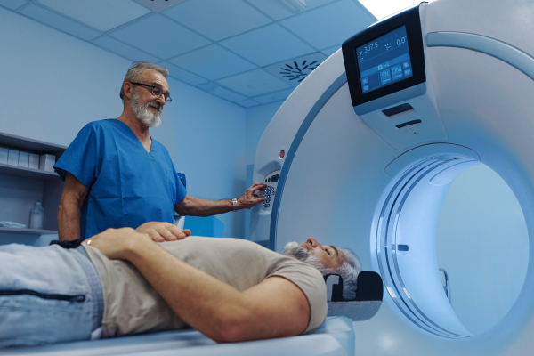 Male patient undergoing X-ray examination using a tilting radiographic wall stand.