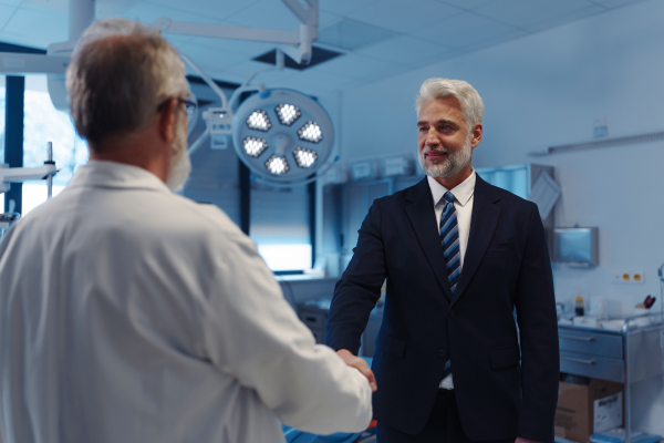 Portrait of pharmaceutical sales representative shaking hand with doctor. Hospital director, manager of private medical clinic.