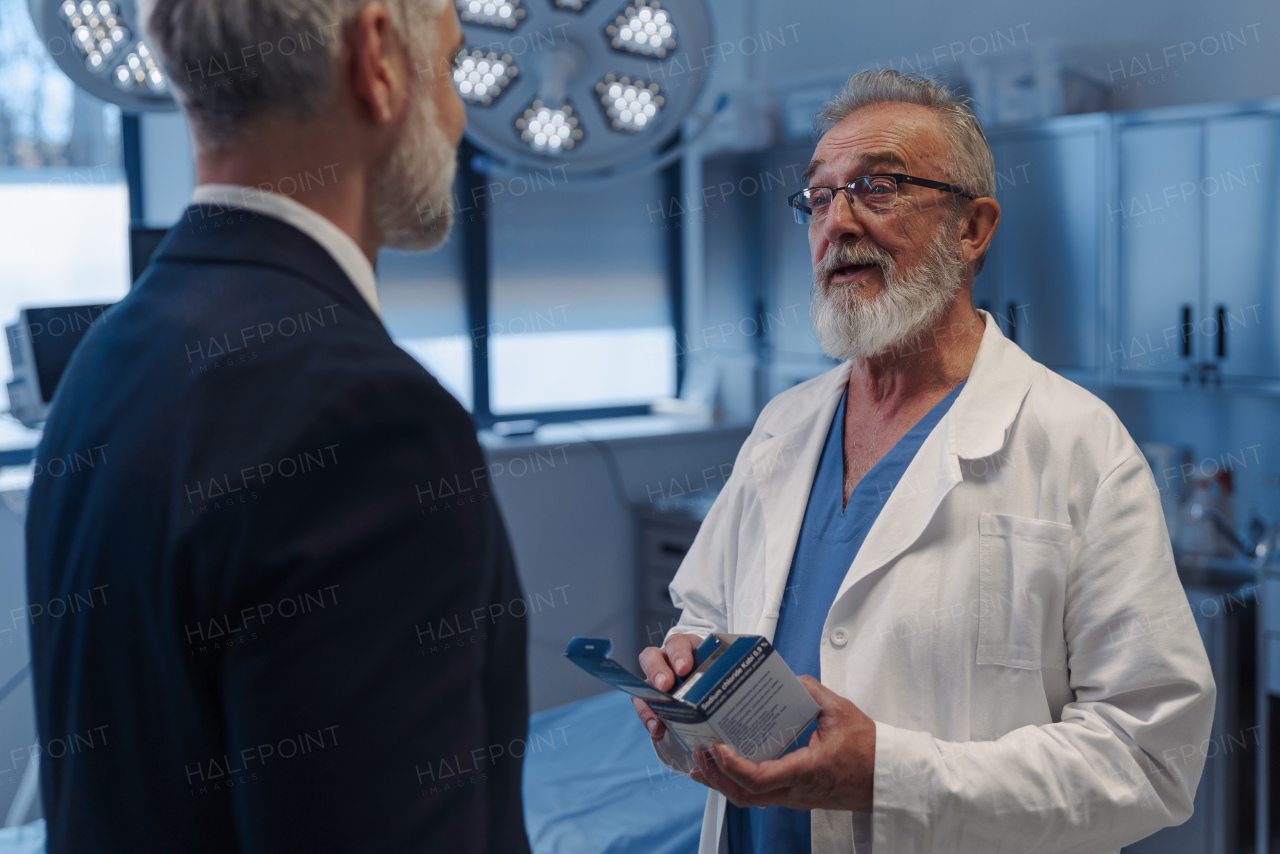 Medical sales representative presenting new medication to doctors, standing in examination room. Hospital setting.