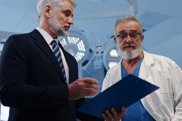 Doctor talking with hospital manager, standing in examination room in clinic.