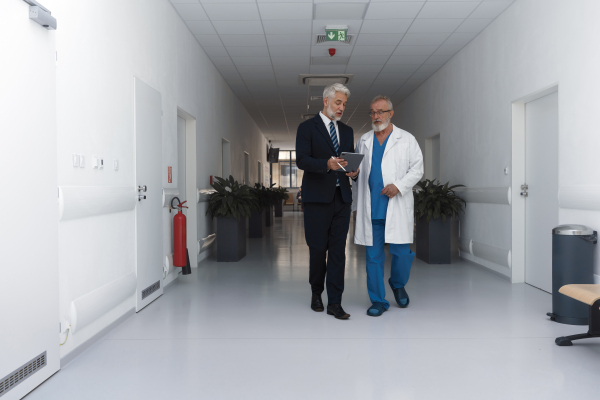 Doctor talking with hospital manager, walking down the hospital hallway.