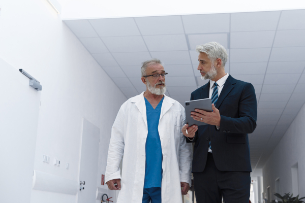Doctor talking with hospital manager, walking down the hospital hallway.