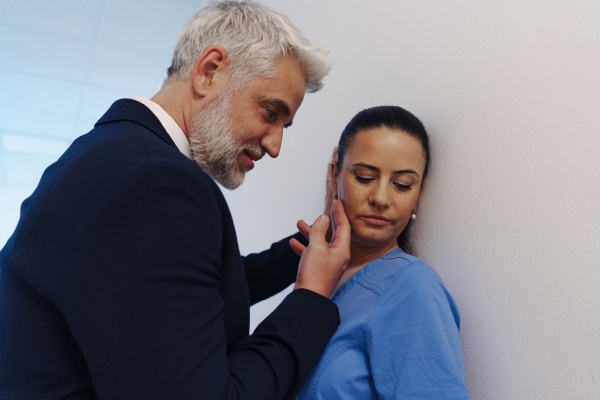 Pharmaceutical representative or hospital manager harassing attractive nurse in healthcare setting.