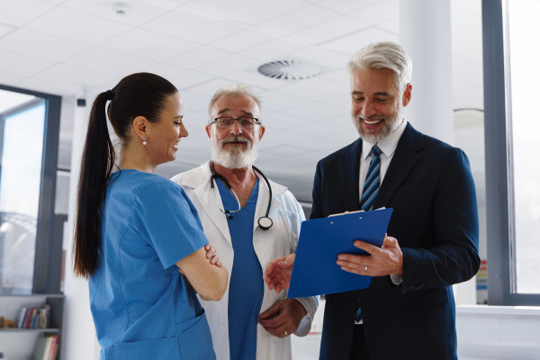 Medical sales representative presenting new medication to doctors, standing hospital hallway. Hospital setting.