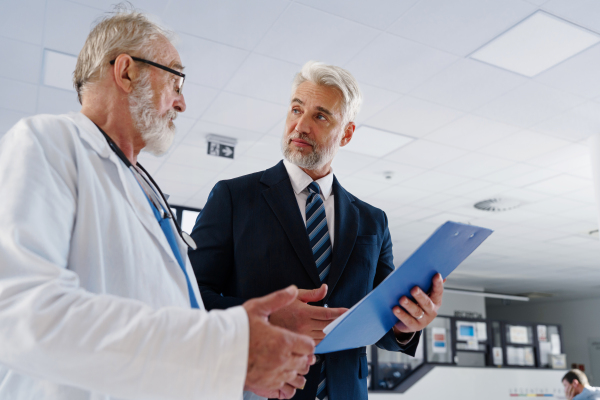 Doctor talking with hospital manager, walking down the hospital hallway.