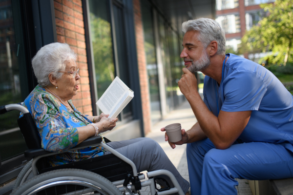 Senior woman in wheelchair reading poems to male caregiver.