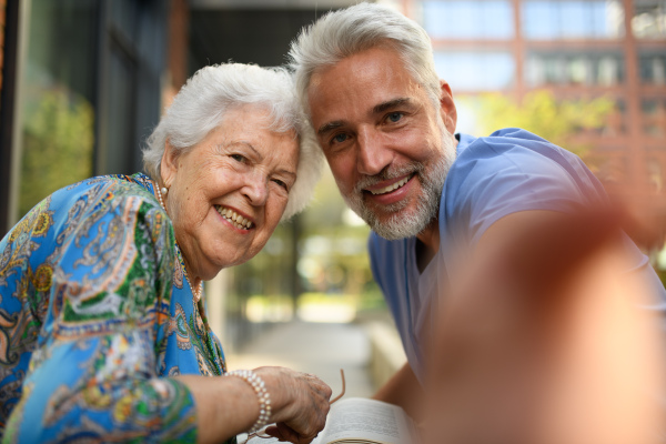 Male caregiver taking selfie with female senior patient.