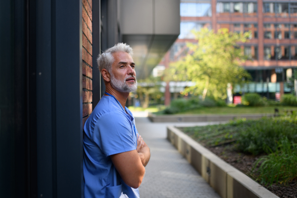 Healthcare worker outside hospital wearing medical uniform.