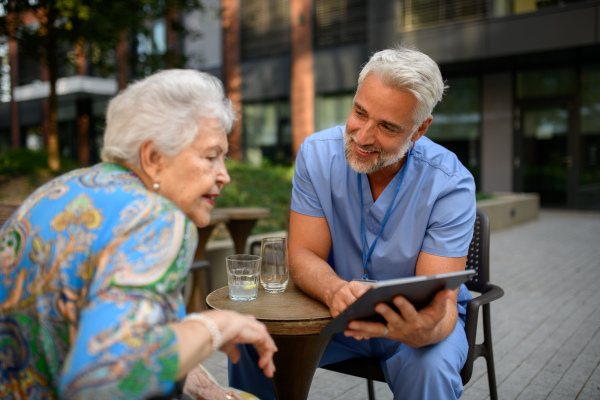 Doctor explaining medication to senior patient and answering her questions about diagnosis.