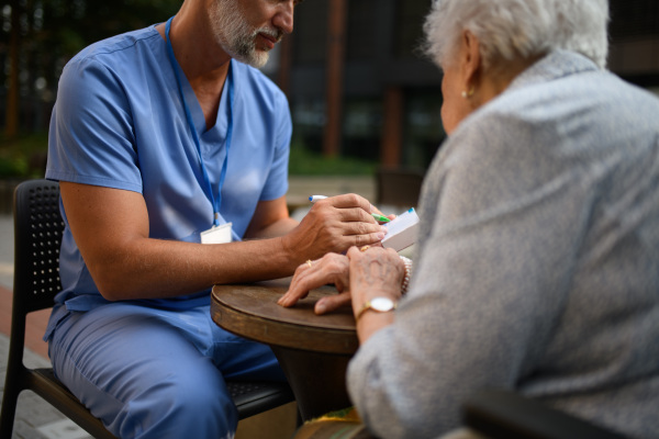 Doctor explaining medication to senior patient and answering her questions about diagnosis.