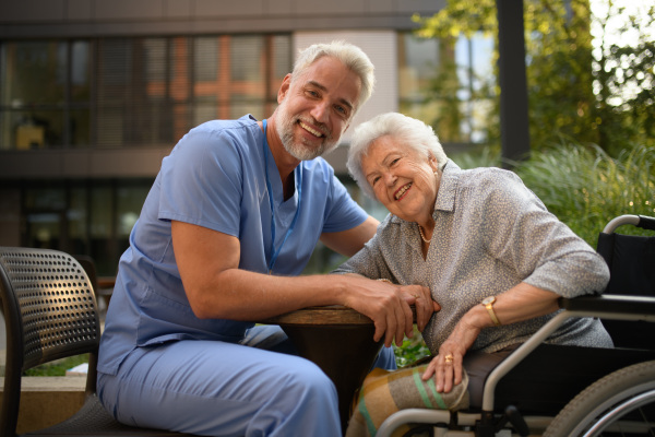Male caregiver talking with senior woman in a wheelchair.