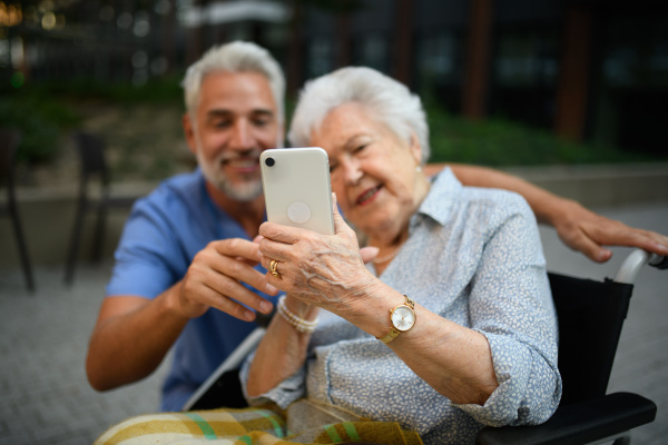 Male caregiver looking at photos with senior woman in a wheelchair.