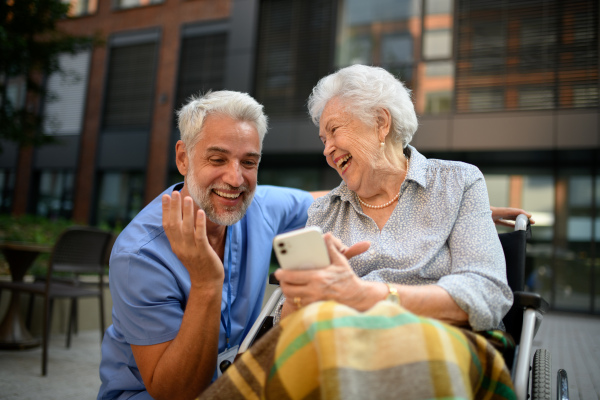 Male caregiver looking at photos with senior woman in a wheelchair.