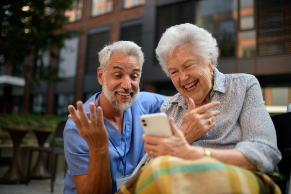 Male caregiver looking at photos with senior woman in a wheelchair.