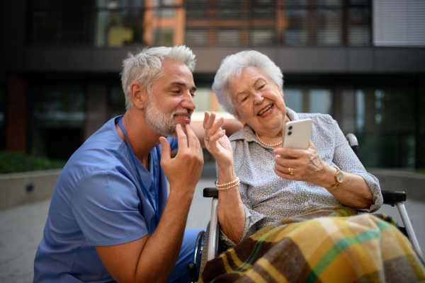 Male caregiver looking at photos with senior woman in a wheelchair.
