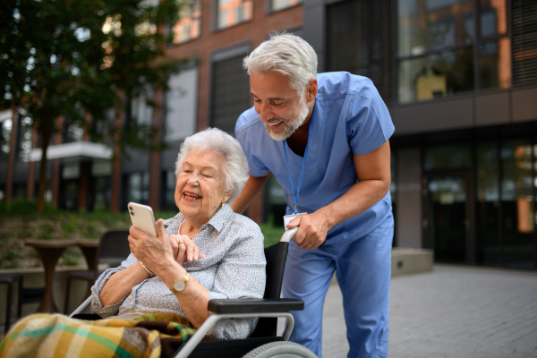 Male caregiver looking at photos with senior woman in a wheelchair.