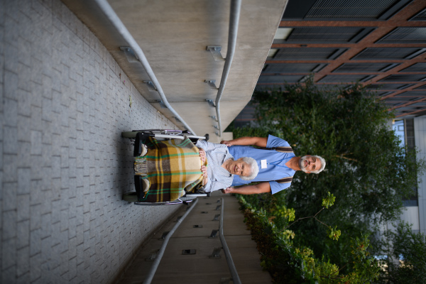 Male caregiver pushing senior woman in a wheelchair.