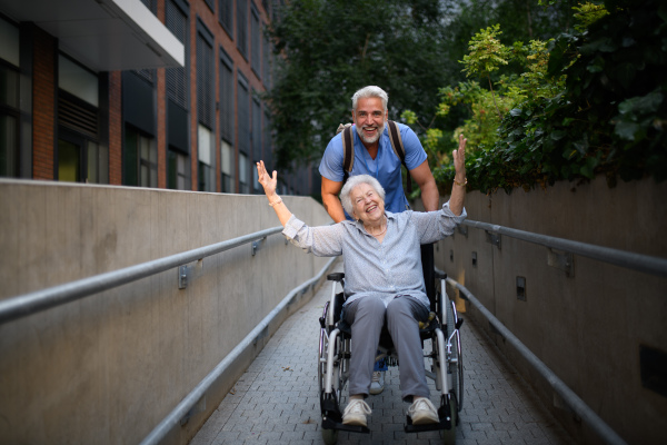 Male caregiver pushing senior woman in a wheelchair.