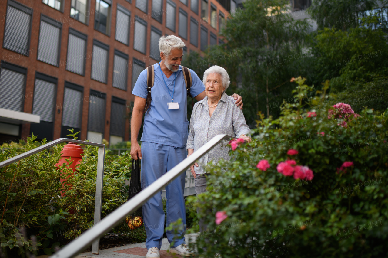 Caring healthcare worker helping elderly woman walk down the stairs.