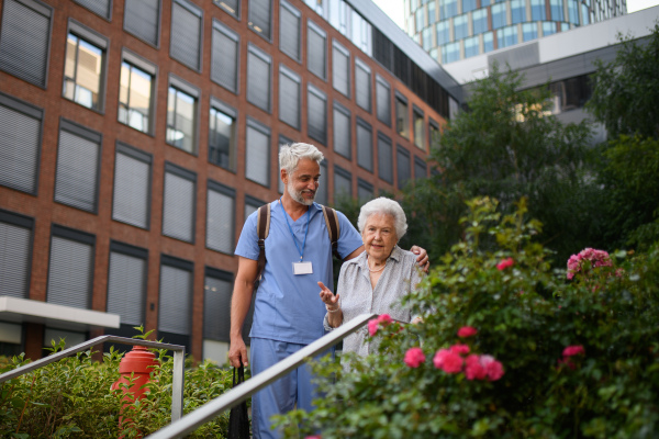 Caring healthcare worker helping elderly woman walk down the stairs.