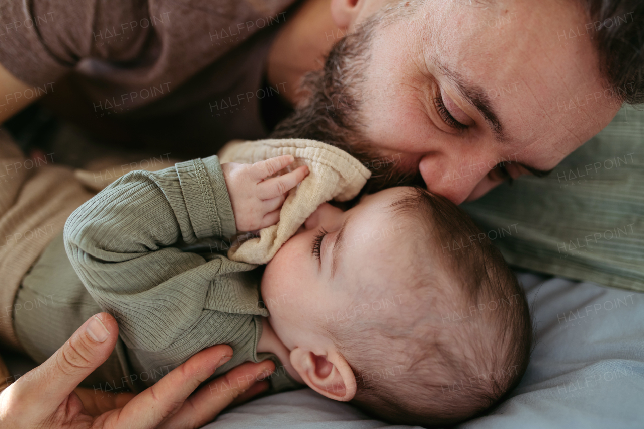 Father putting the baby to sleep, lying next to him in the crib and soothing him.