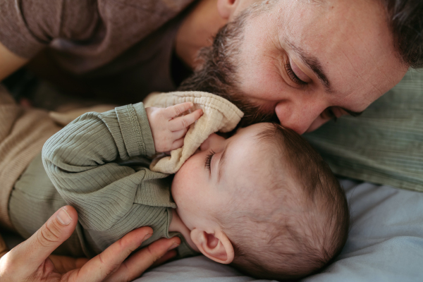 Father putting the baby to sleep, lying next to him in the crib and soothing him.
